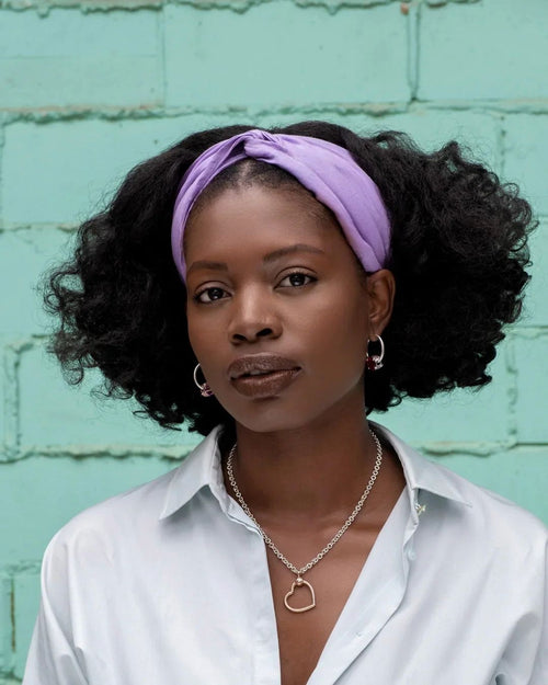 Woman with natural curly hair wearing a lavender twisted headband