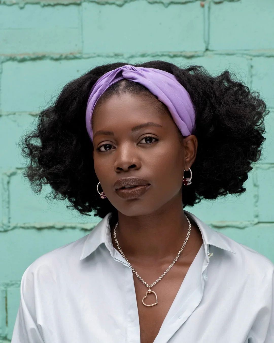 Woman with natural curly hair wearing a lavender twisted headband