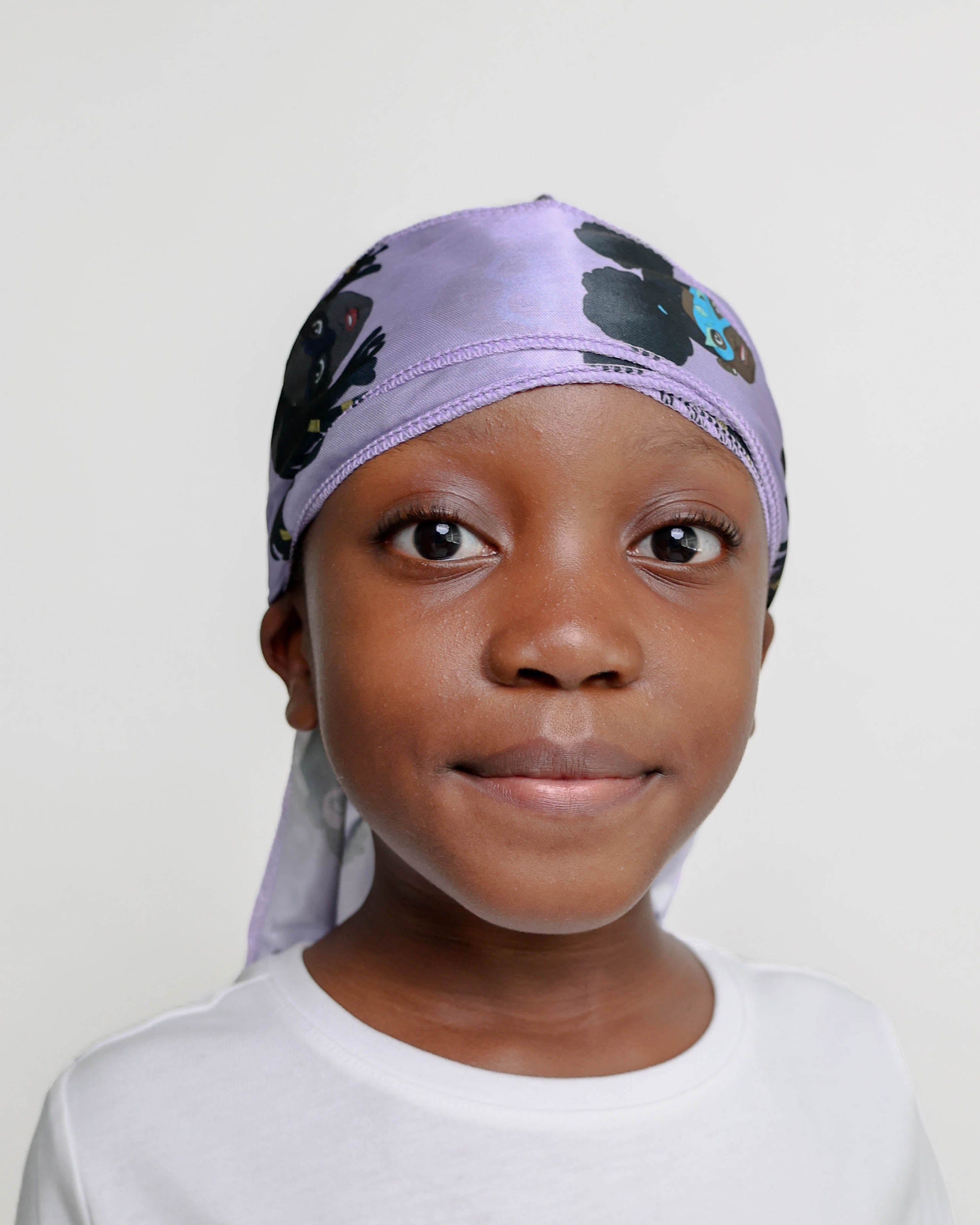 Child wearing a purple durag with black and brown superhero's on a plain background