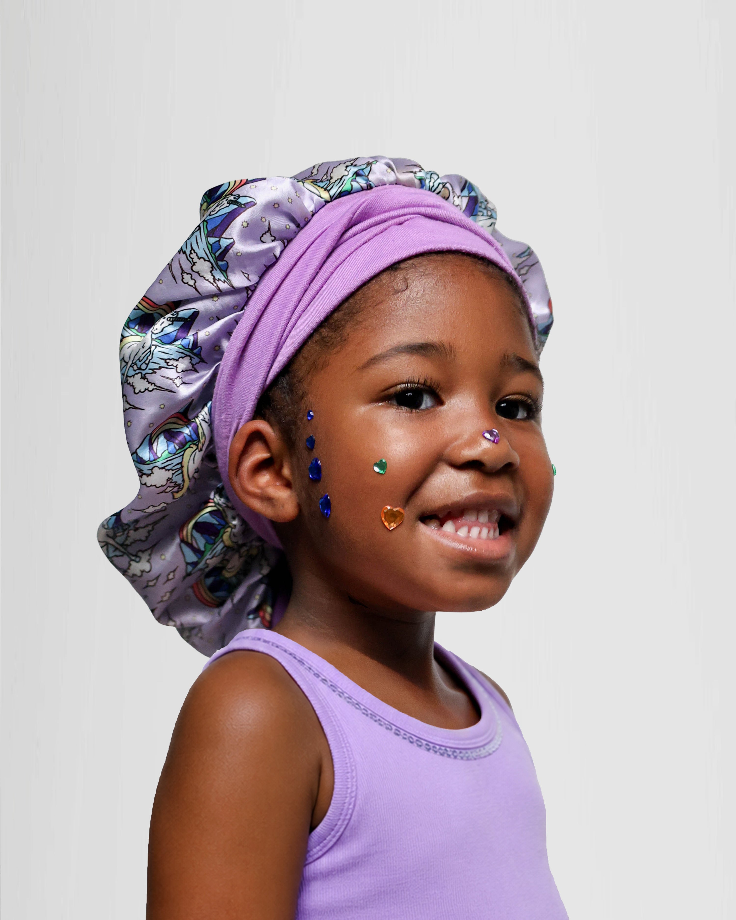 Child wearing a purple unicorn patterned bonnet on a plain background